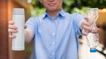 young asian man's hands holding a stainless steel reusable water bottle and single use plastic drinking bottle which become a huge daily waste. Say no to plastic, Zero waste, Eco